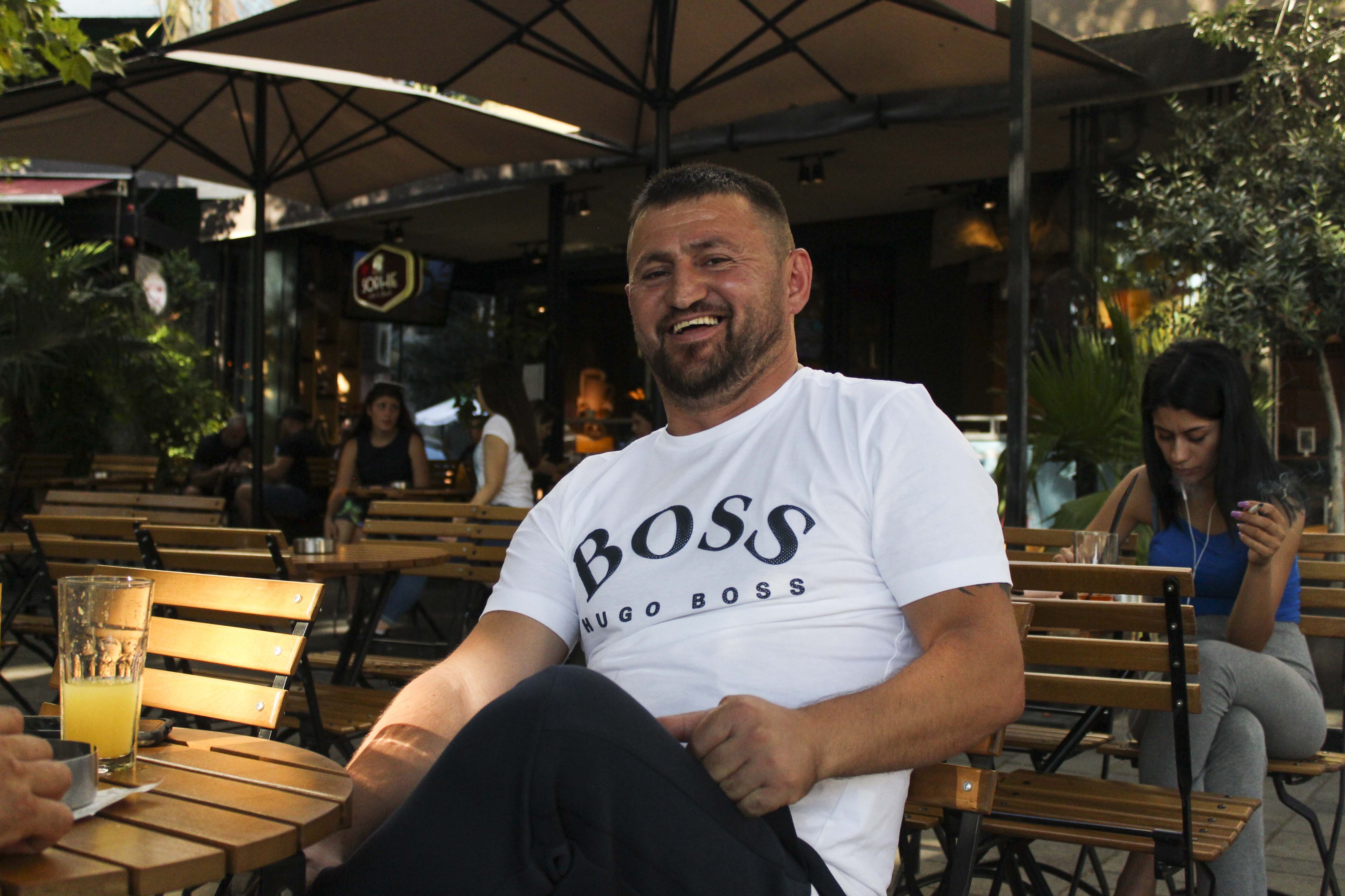 A man sitting alone at an outdoor cafe in Tirana, Albania poses shows off his âBOSSâ T-shirt on Thursday, Aug. 27, 2020. (Photo by Meng Wei)